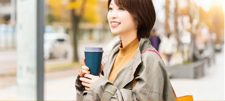 高田馬場での新生活を楽しむ女性。成約特典のギフトカードやコーヒーチケットで、引っ越し後のおしゃれなカフェタイムを過ごすイメージ。